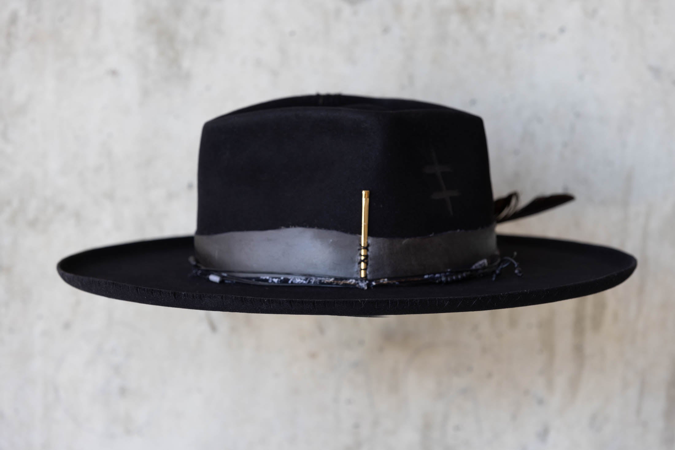 A black beaver felt hat with leather band and wide brim left side