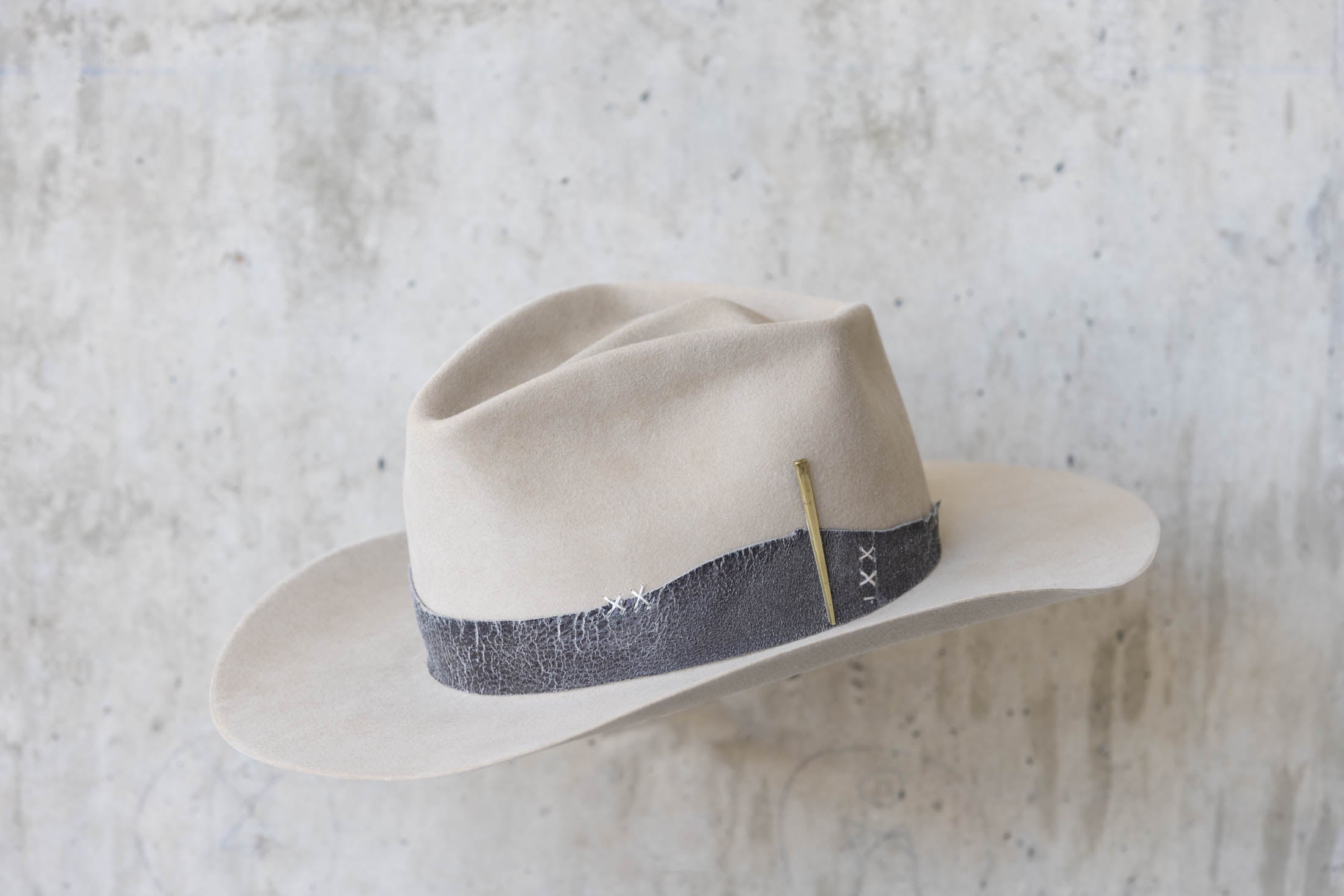 A beige western beaver felt cowboy hat with a leather band and brass nail detail for men and women angle