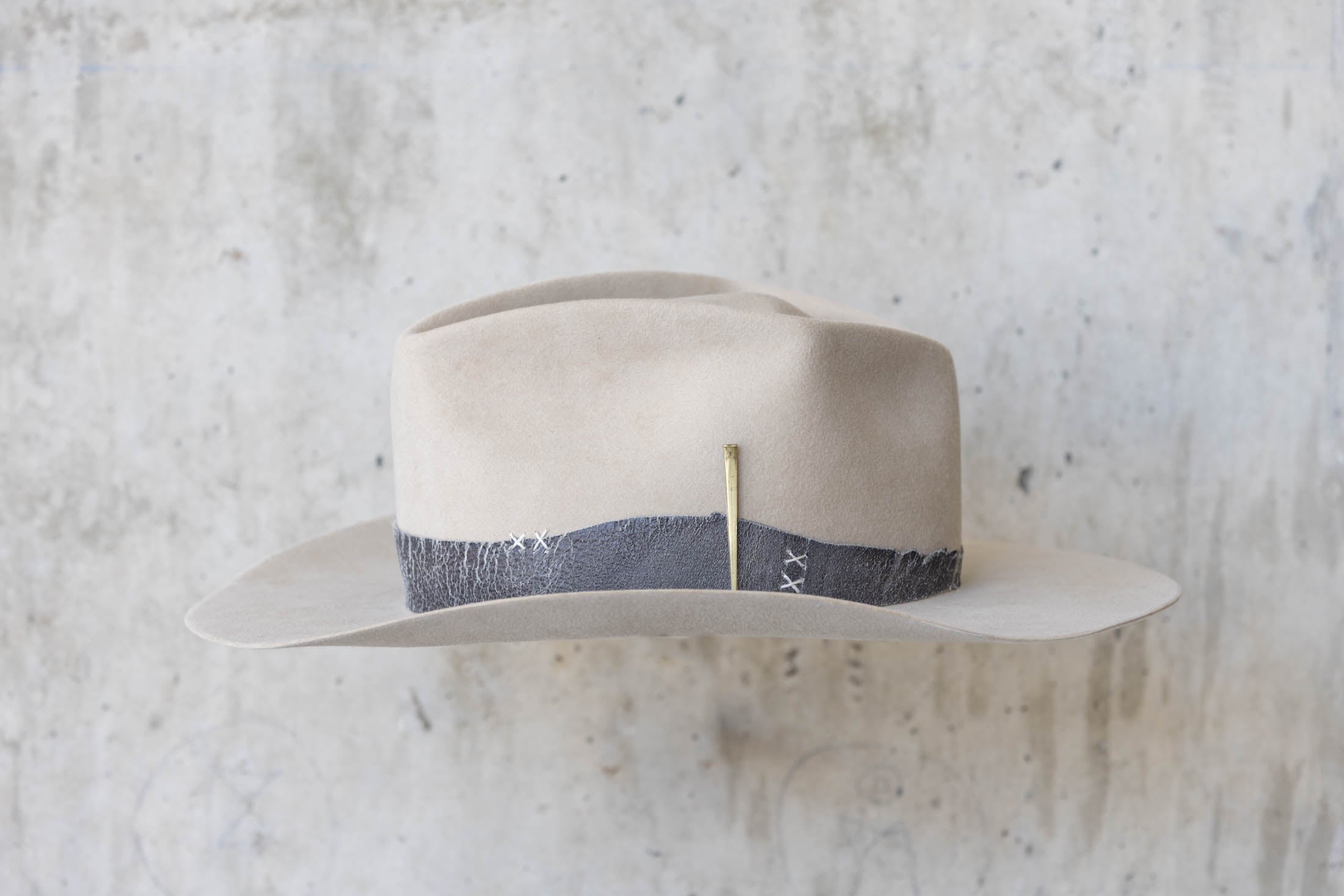 A beige western beaver felt cowboy hat with a leather band and brass nail detail for men and women left
