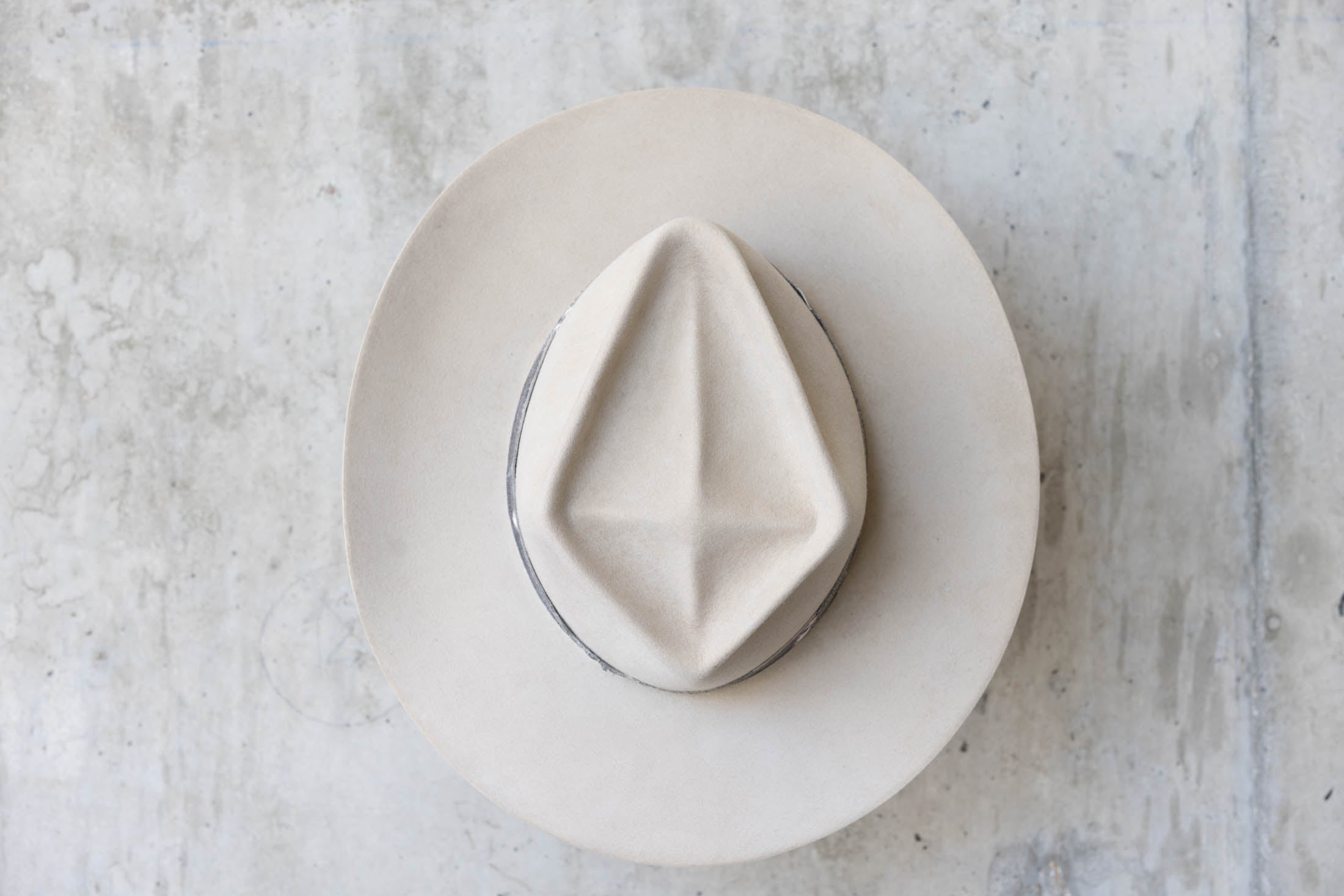 A beige western beaver felt cowboy hat with a leather band and brass nail detail for men and women top