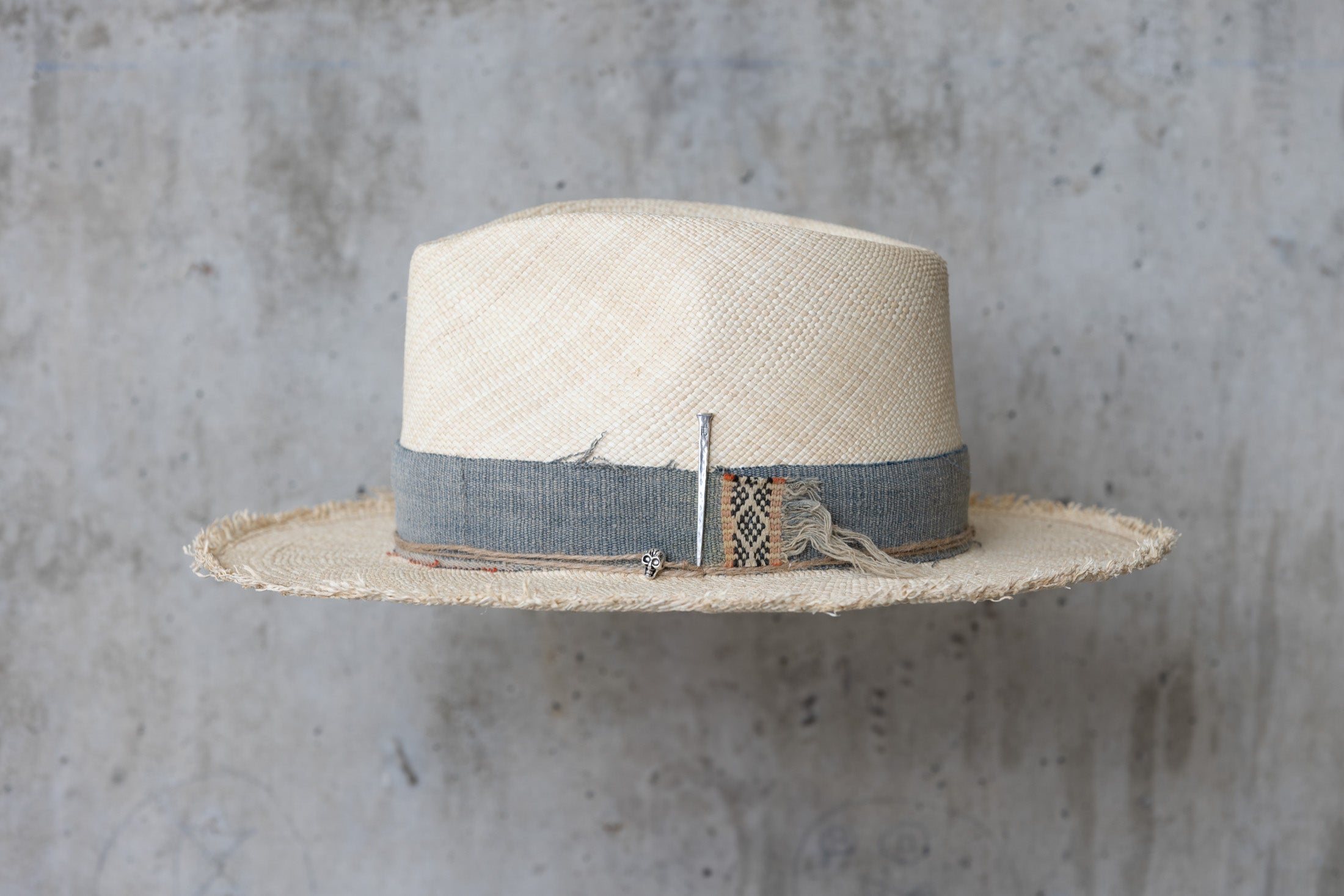 A beige Panama straw hat with a vintage blue band left side