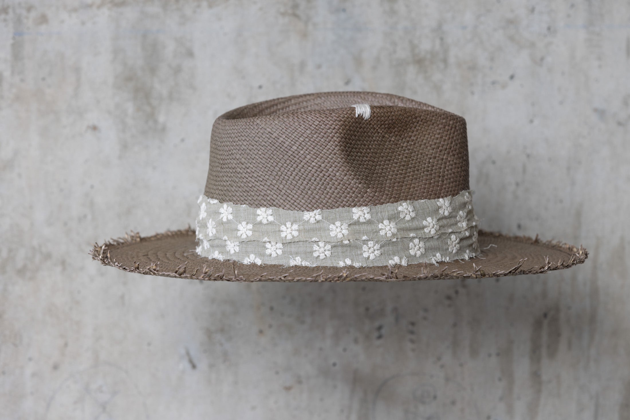 A sage green straw hat with a teardrop crown and linen band with stitched flowers right side