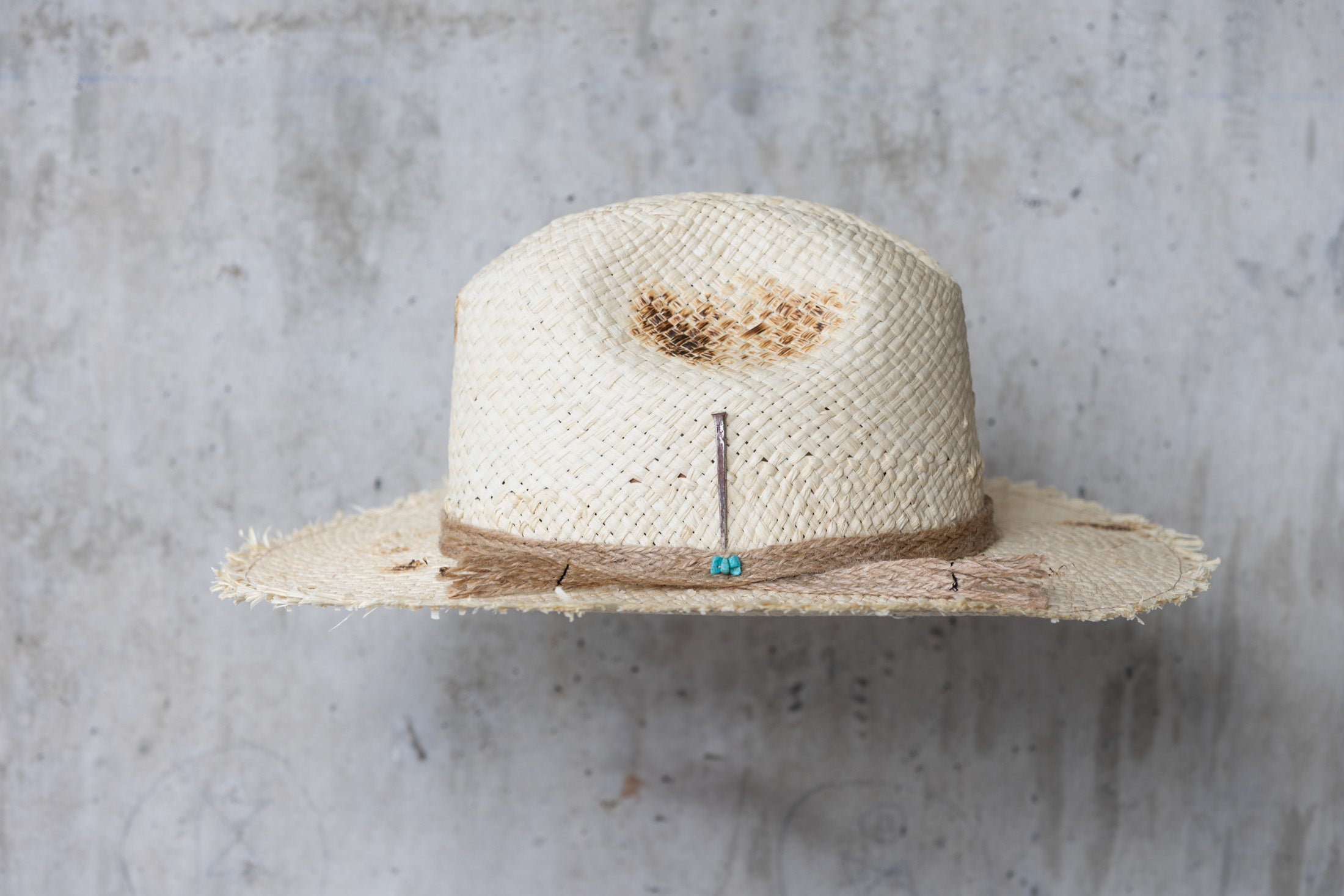 Beige colored straw cowboy hat with twine band and distressed look left side view