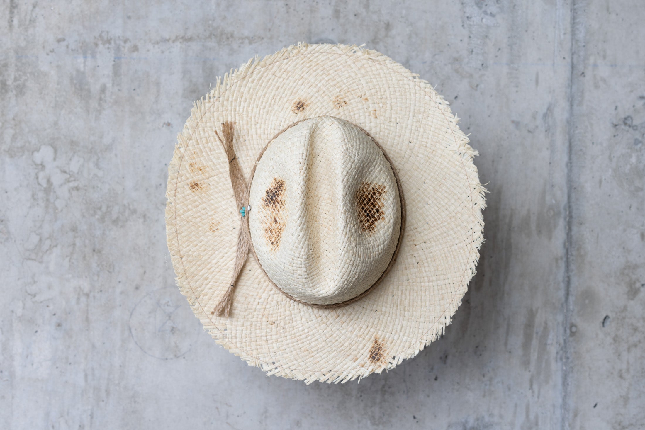Beige colored straw cowboy hat with twine band and distressed look top