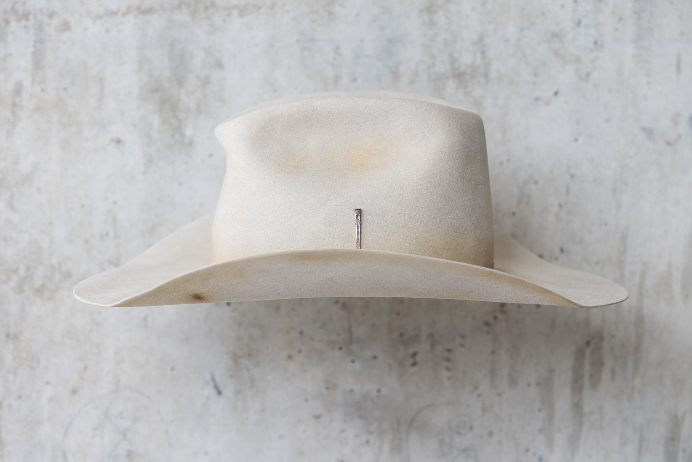 A beige, bone-colored cowboy hat with a mule kick and western flanged brim left side view