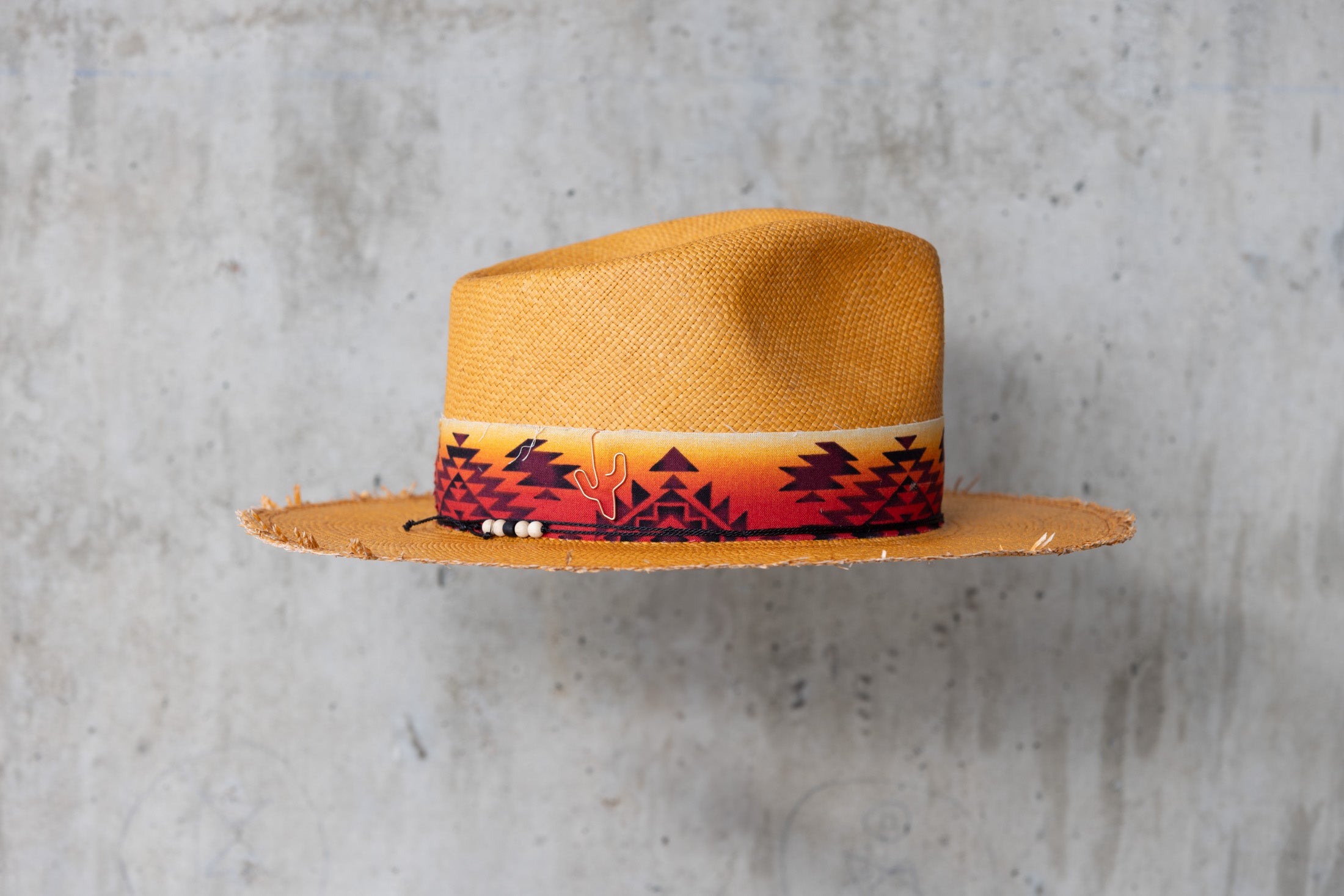 A Caramel colored straw hat with southwestern style band and frayed edge brim right side