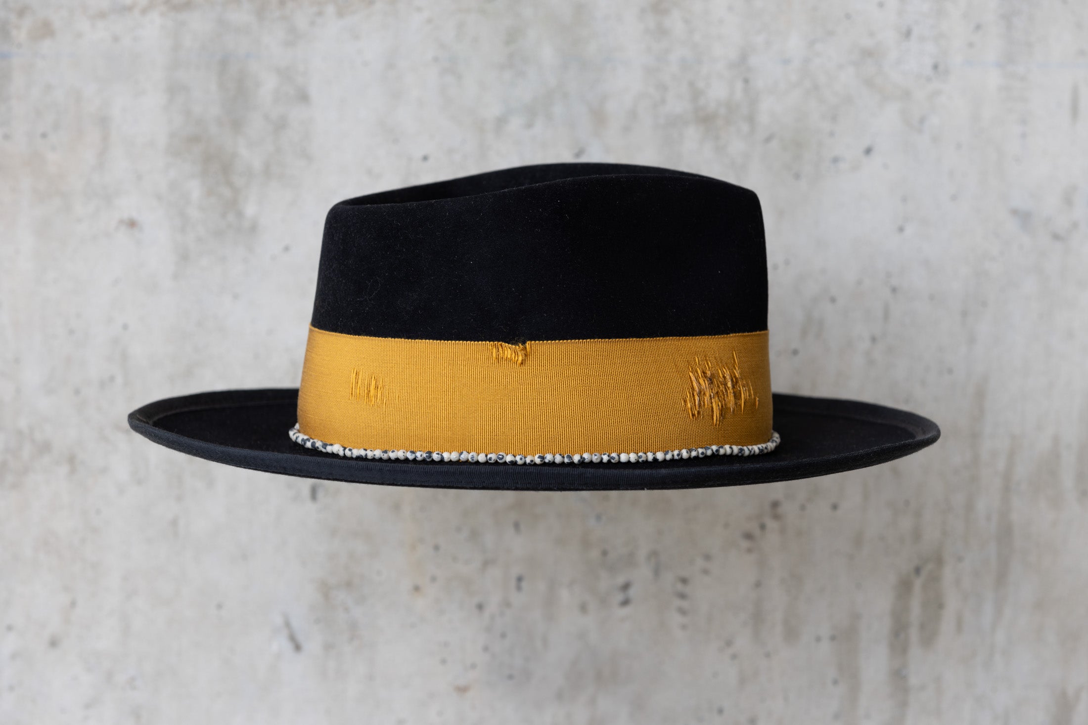 A black beaver felt hat with a yellow band and a teardrop crown right side