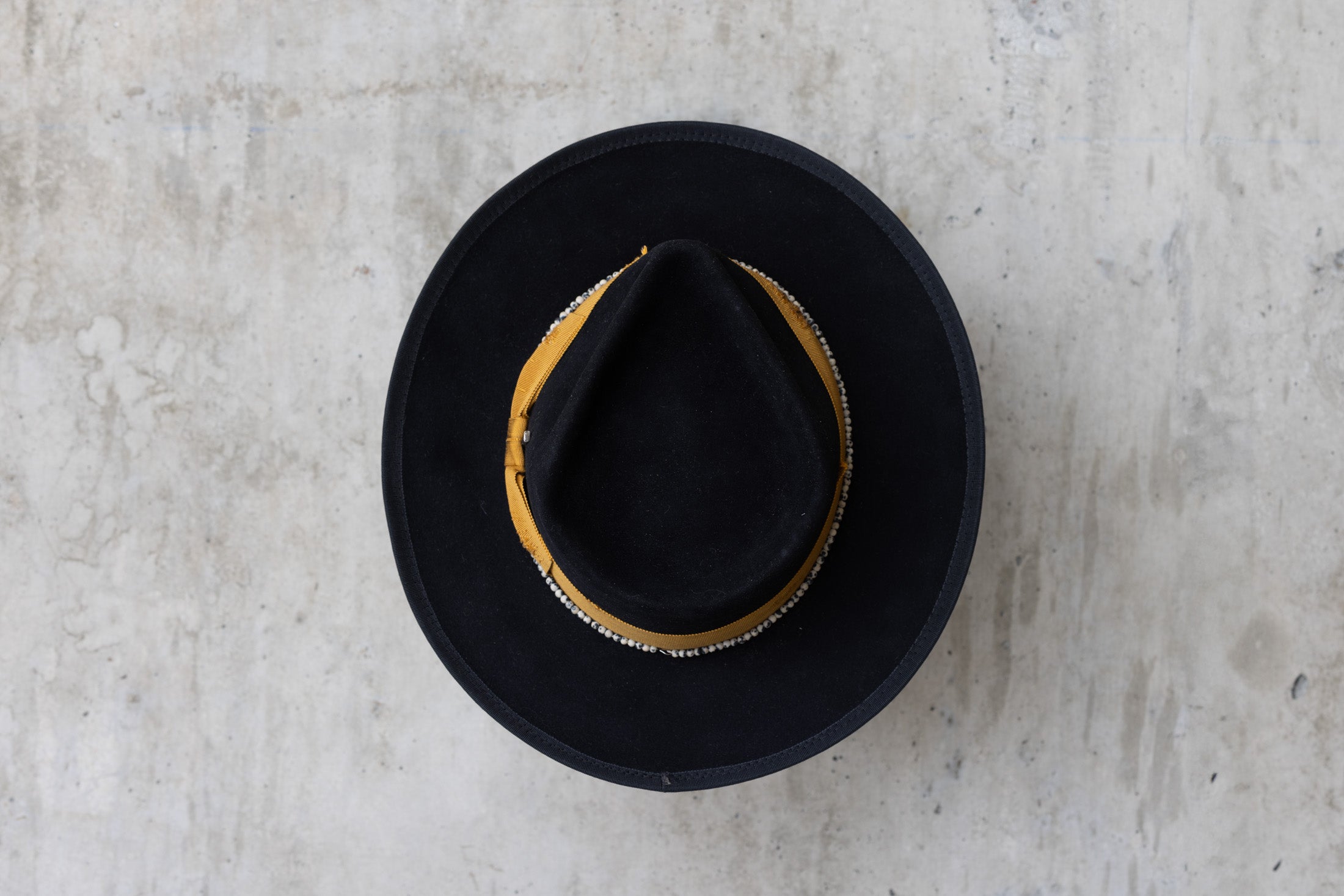 A black beaver felt hat with a yellow band and a teardrop crown top