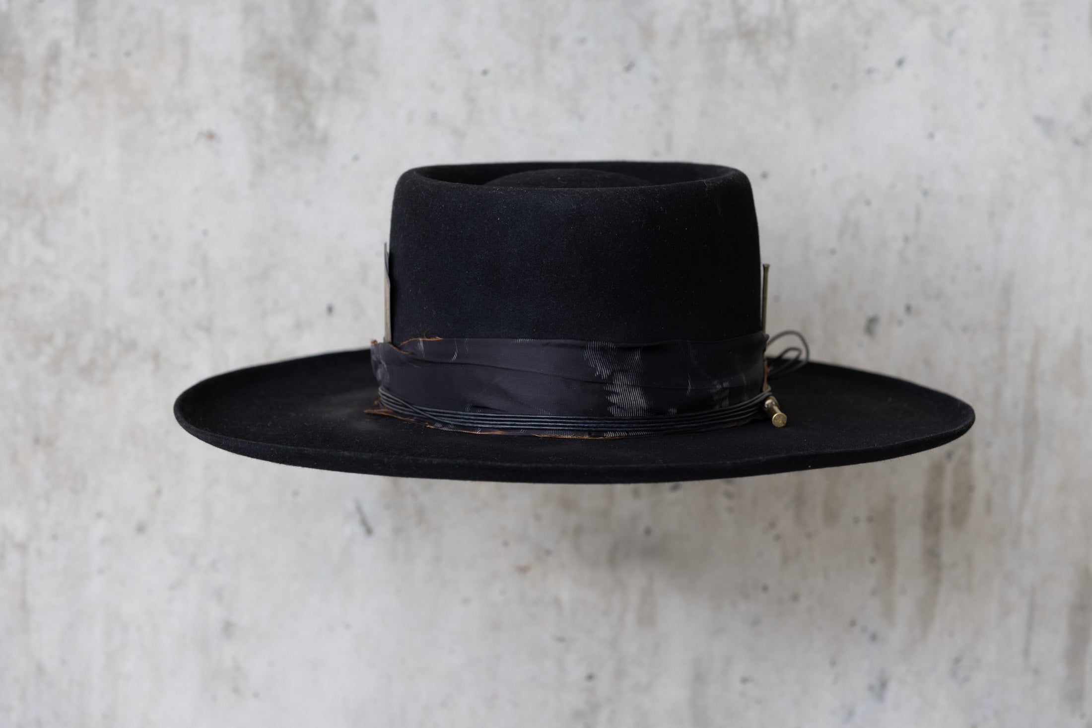 A black Western beaver felt cowboy hat with a wide brim telescope crown and a feather and leather band for men and women front