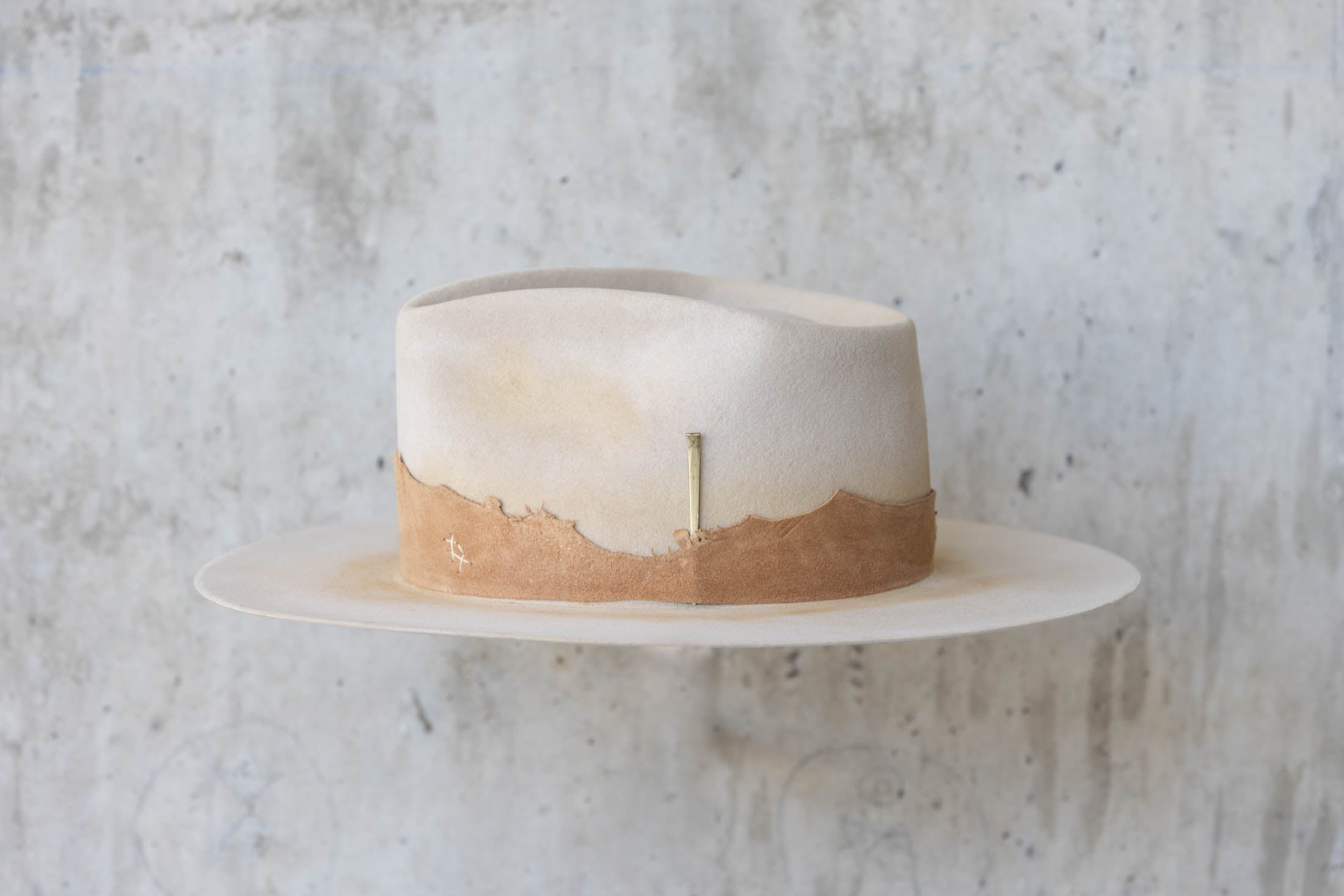 A beige Western hat with a teardrop crown  and brown leather band left side