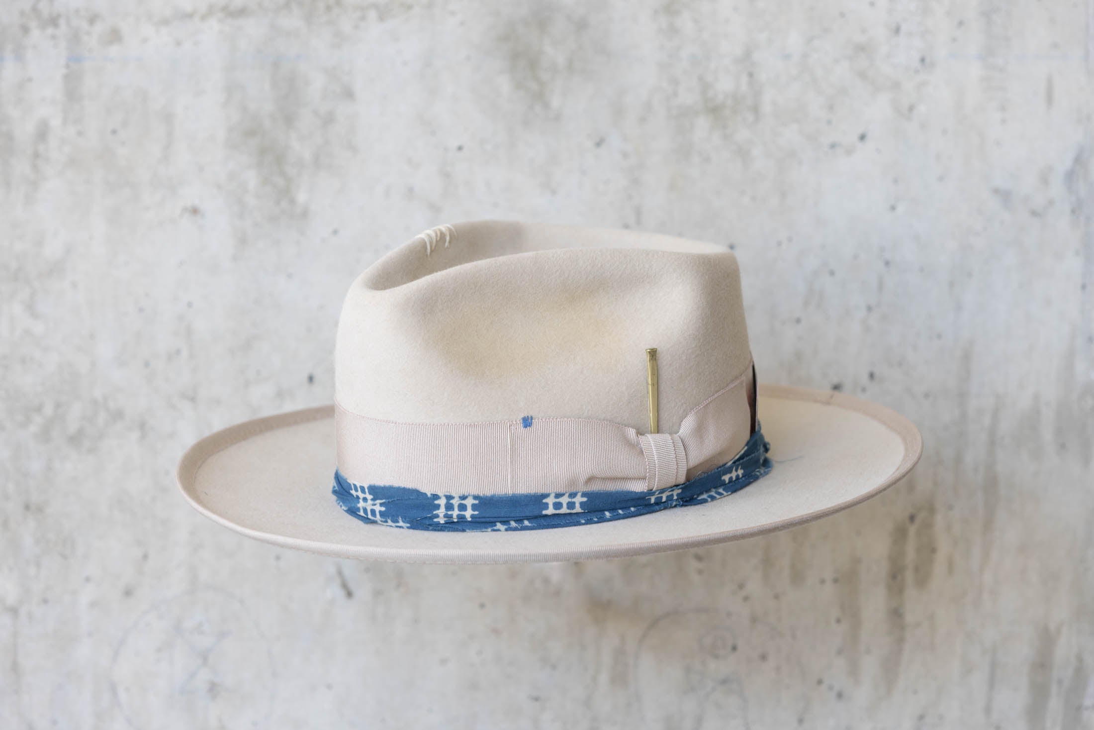 A beige fur hat with a teardrop crown, beige and blue band angle view
