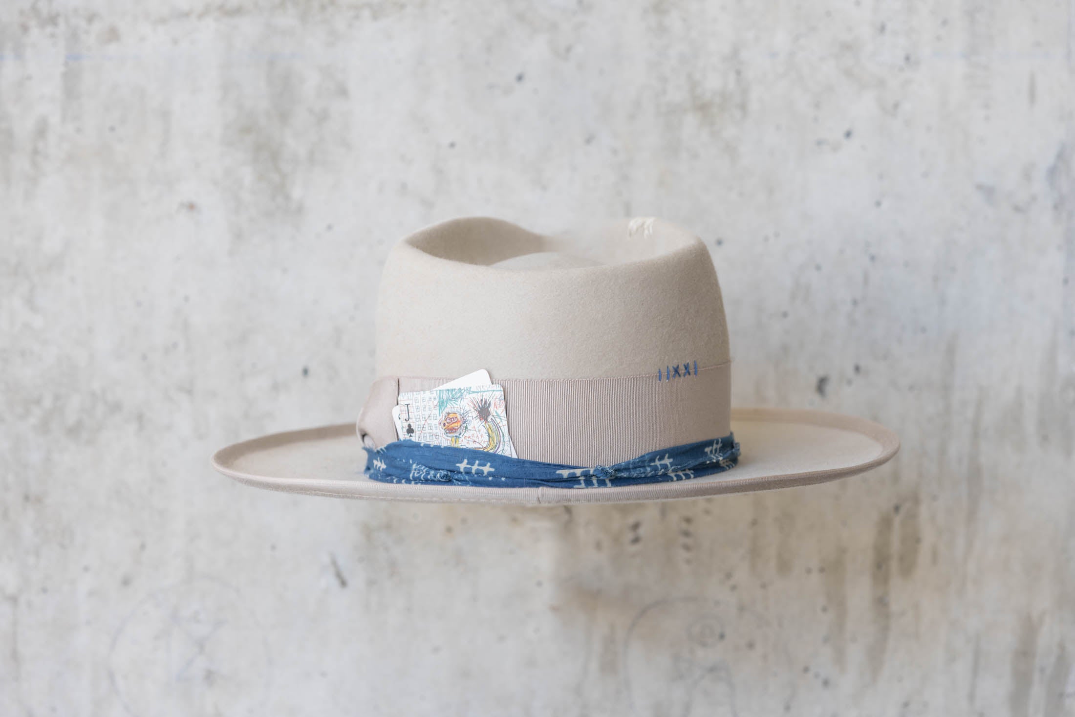 A beige fur hat with a teardrop crown, beige and blue band back side