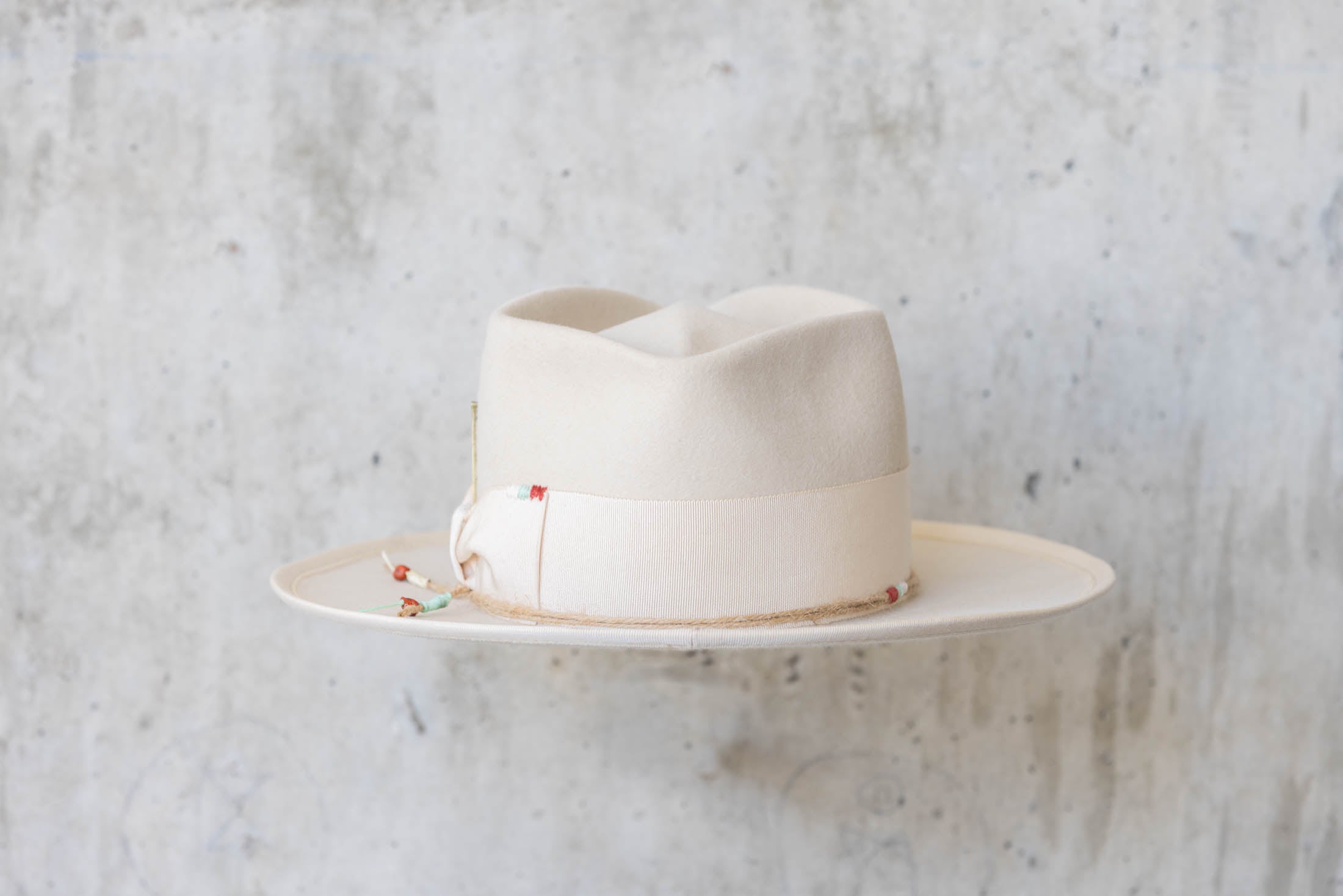A beige beaver felt hat with beige ribbon back side view