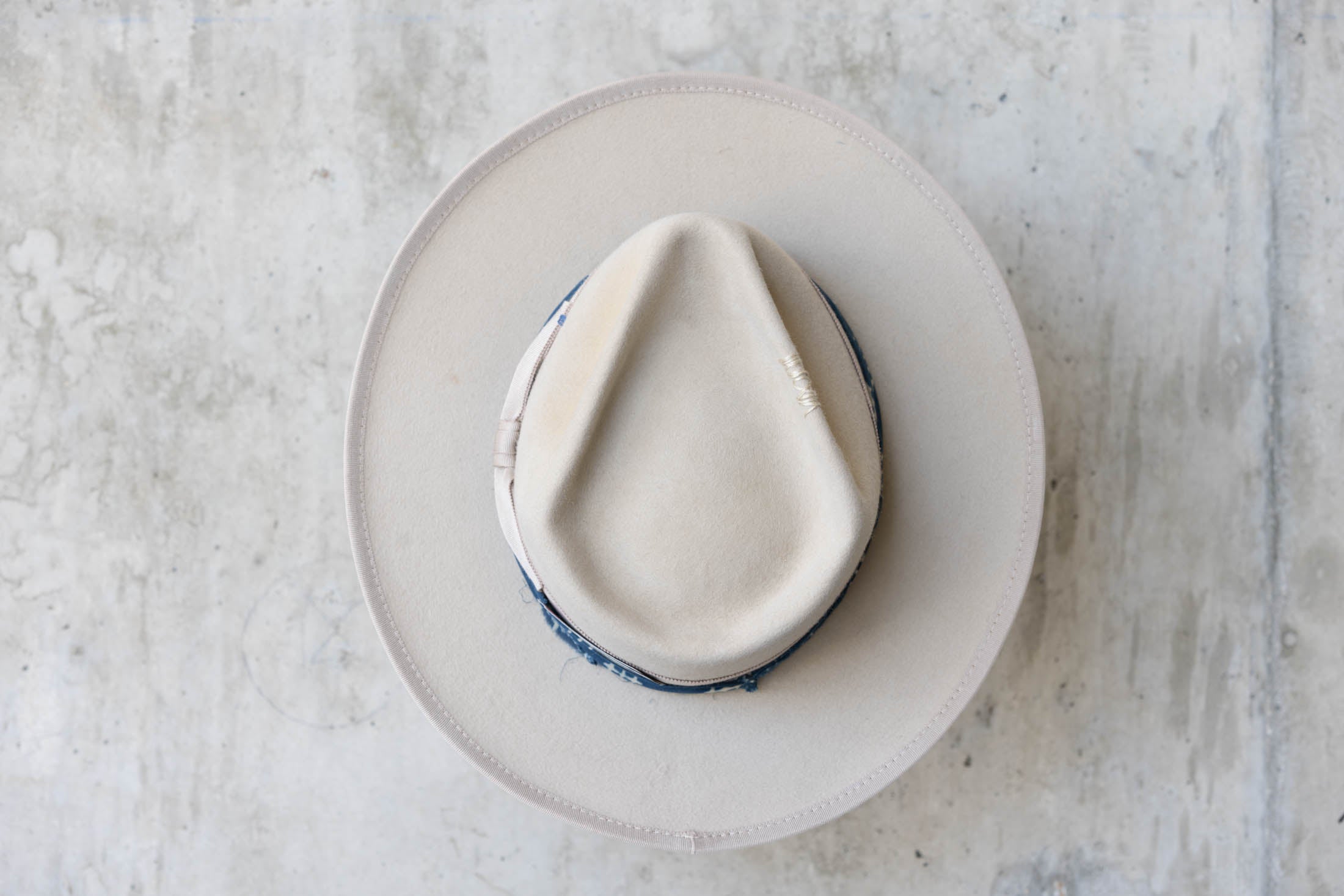 A beige fur hat with a teardrop crown, beige and blue band top