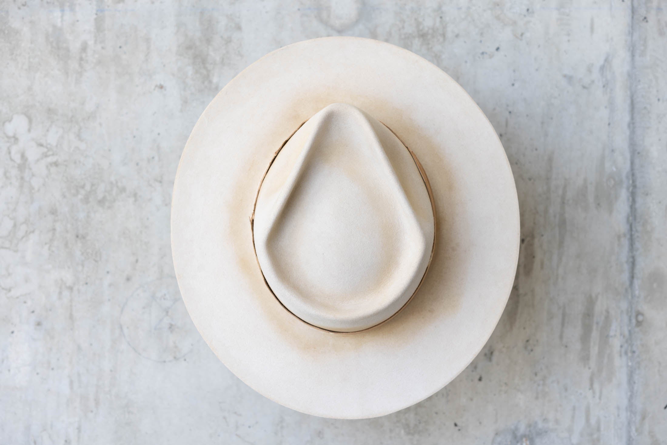 A beige Western hat with a teardrop crown  top