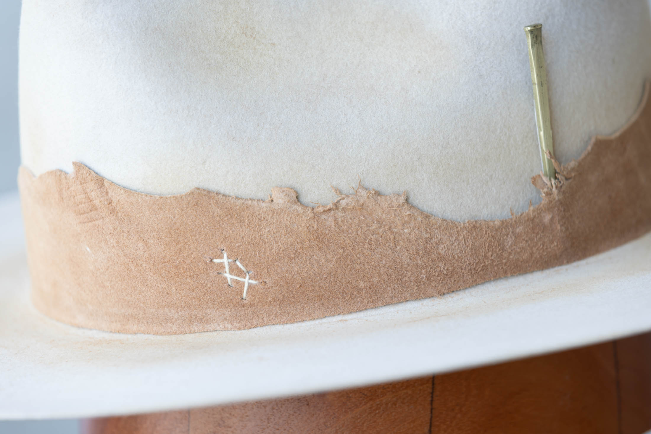 close up view of a beige hat with brown leather band