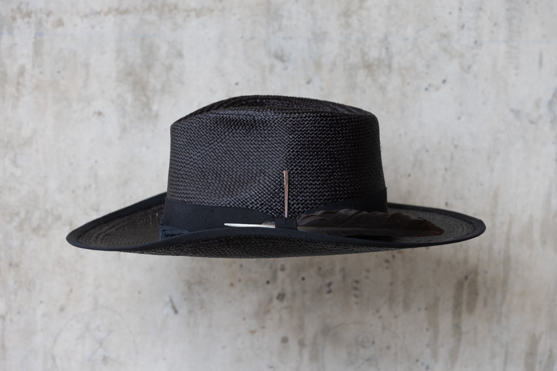 A black straw cowboy hat with a teardrop crown and black band left side