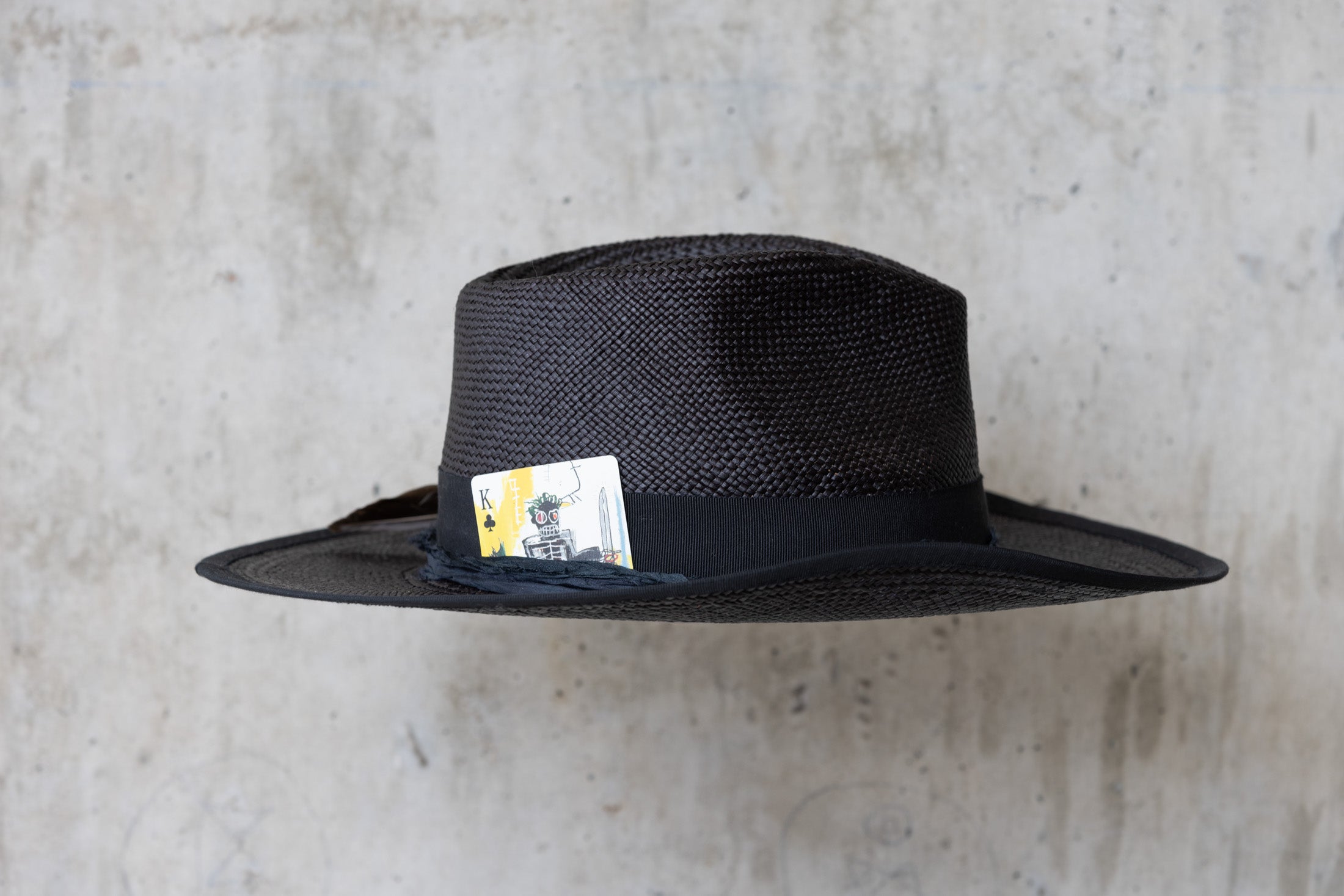A black straw cowboy hat with a teardrop crown and black band right side