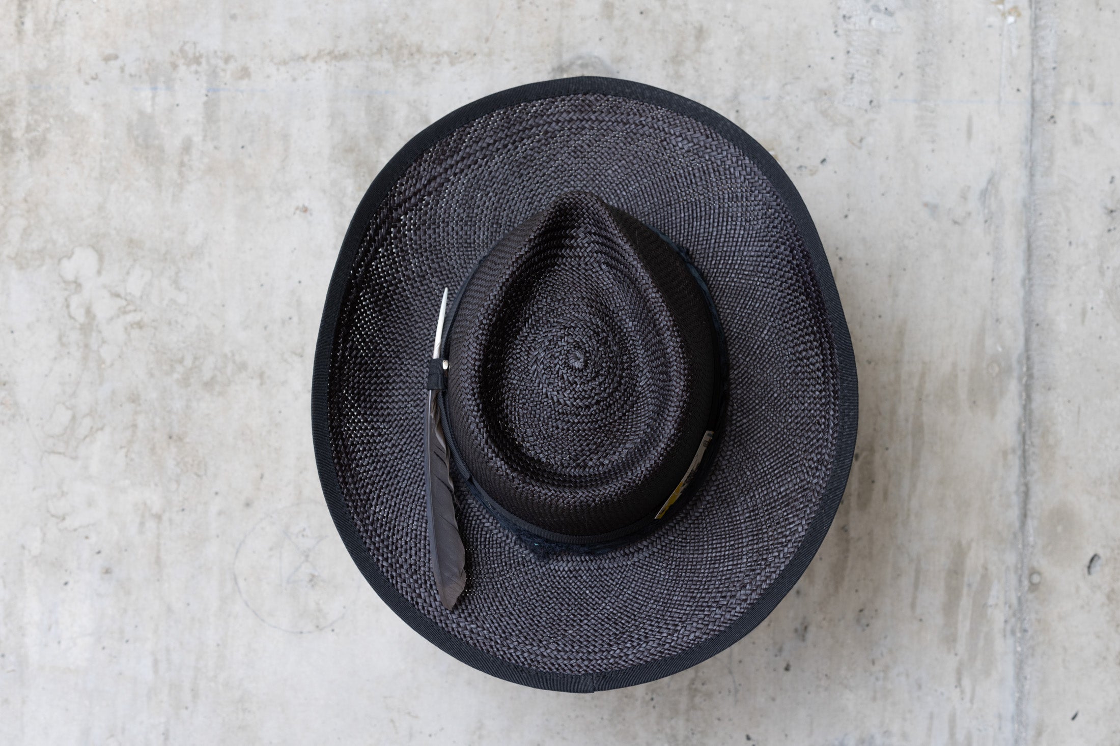 A black straw cowboy hat with a teardrop crown and black band top
