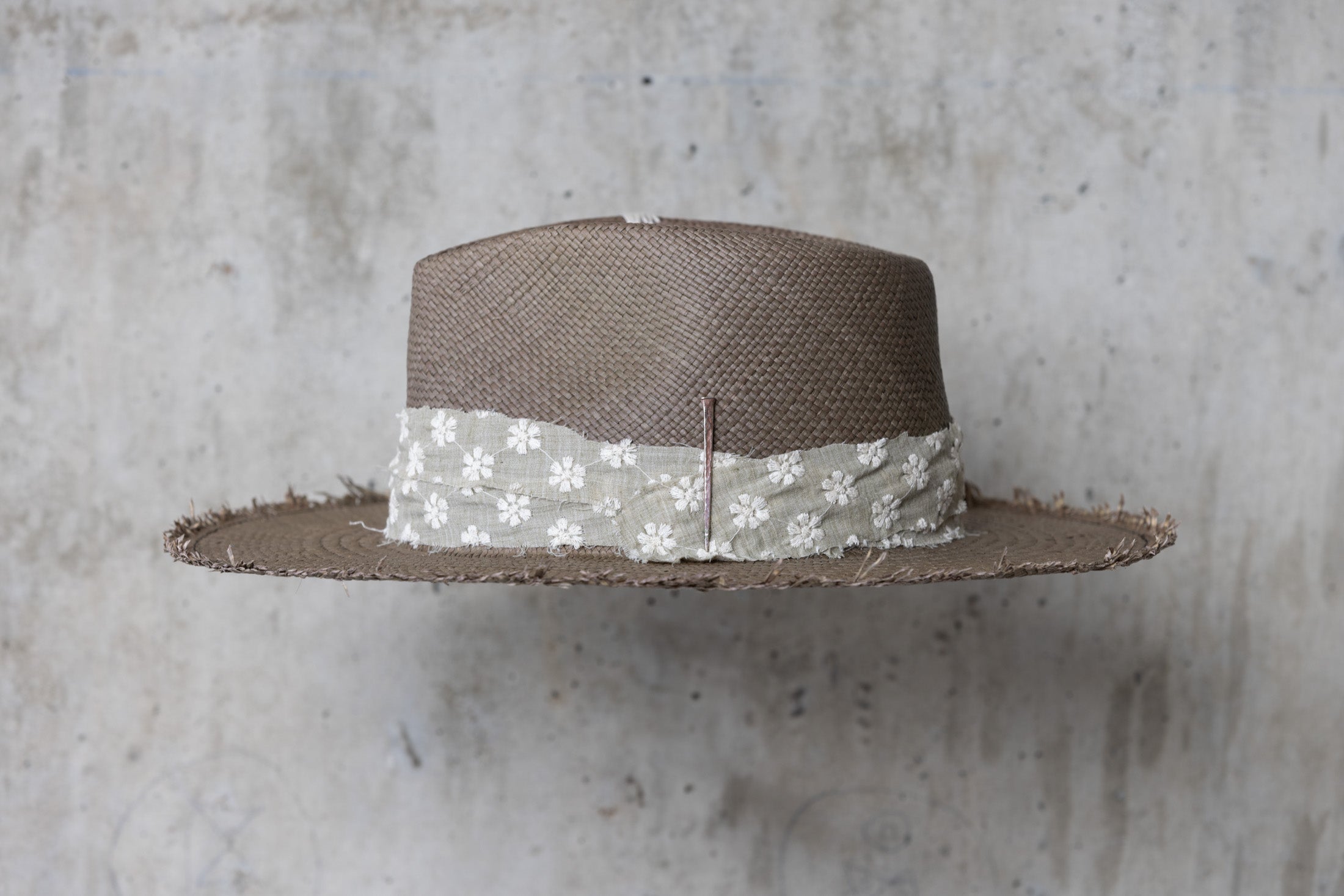 A sage green straw hat with a teardrop crown and linen band with stitched flowers left side