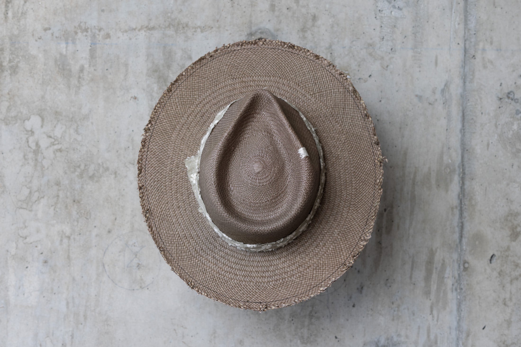 A sage green straw hat with a teardrop crown and linen band with stitched flowers top