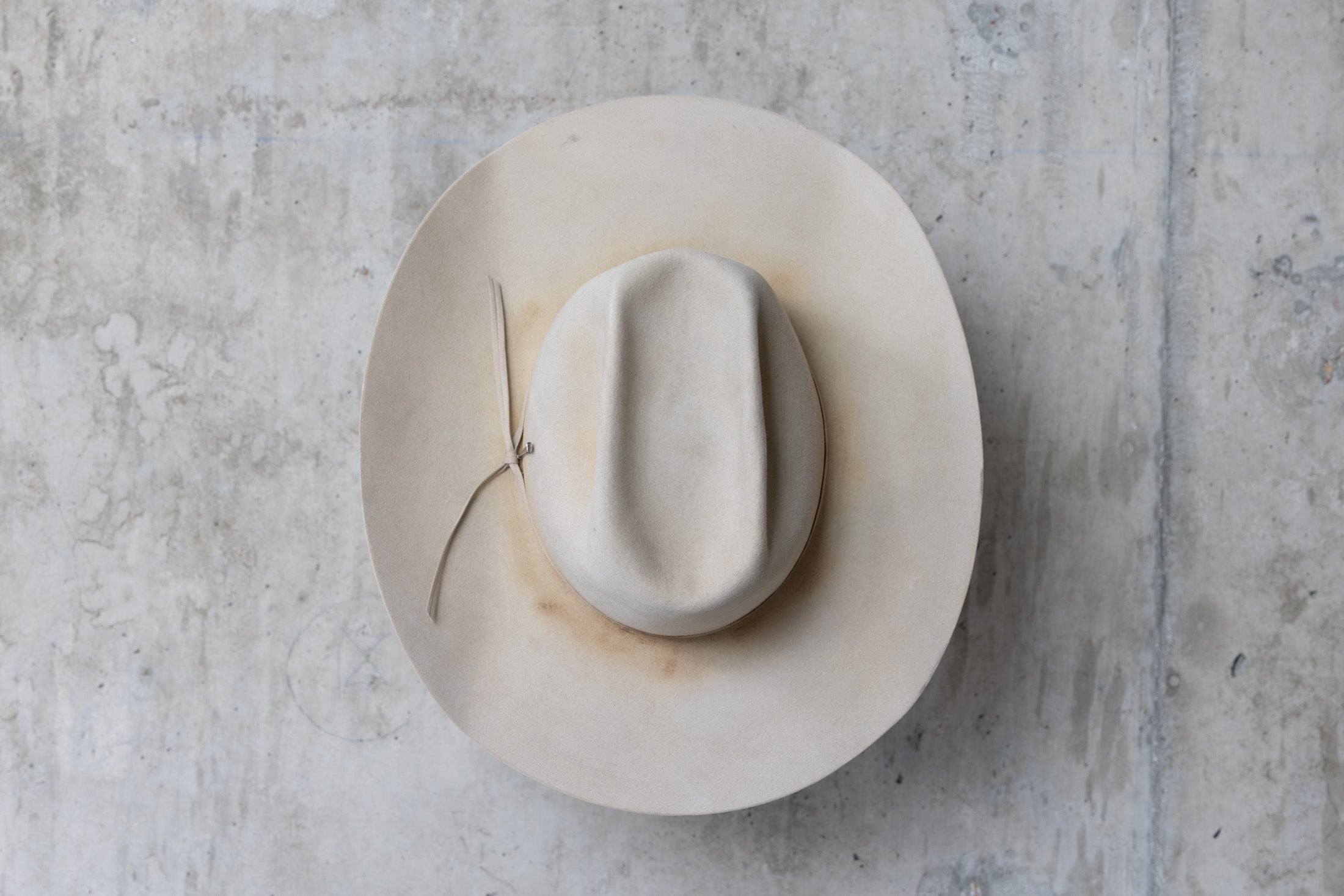 A beige, bone-colored cowboy hat with a mule kick and western flanged brim top view