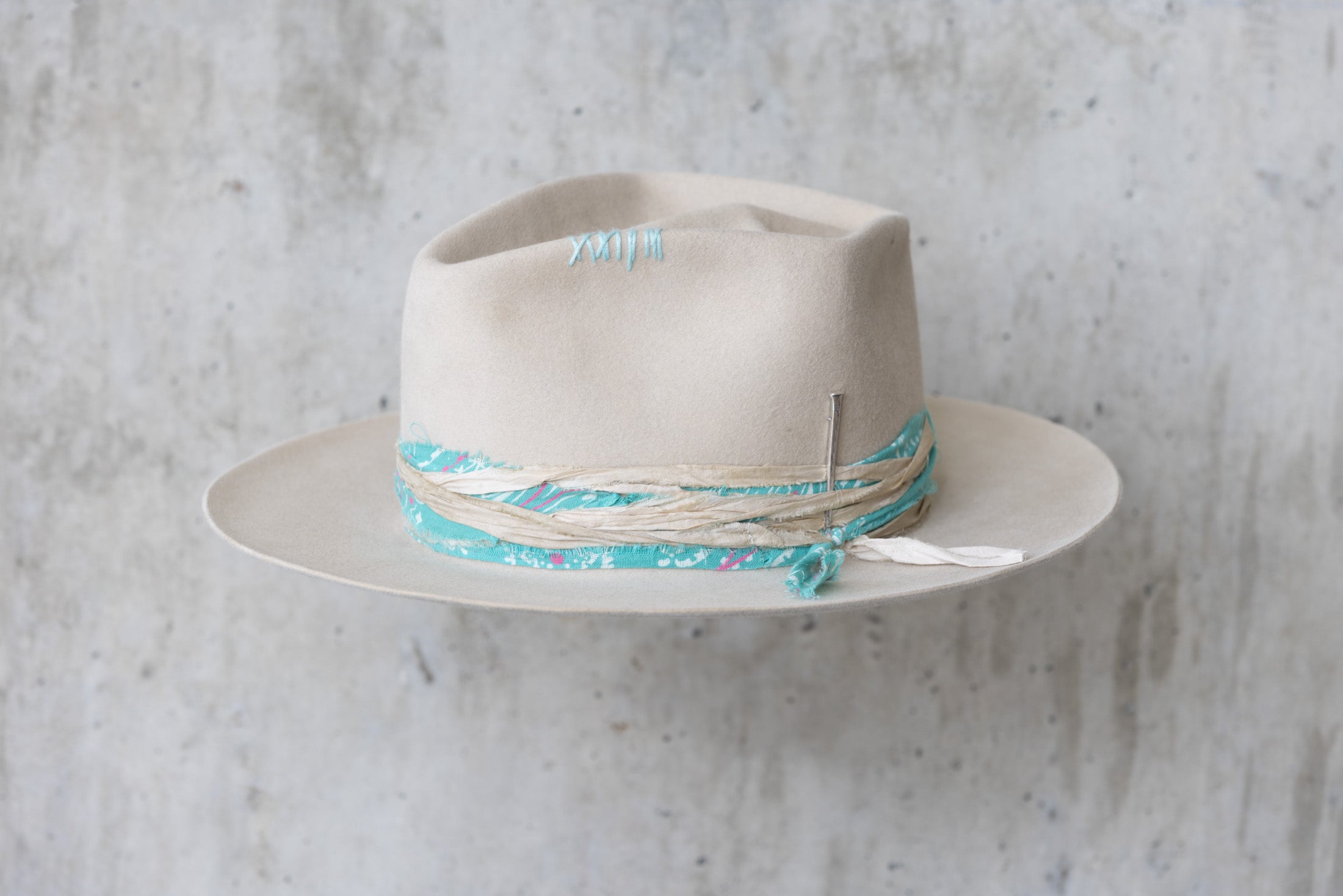 A sand colored fedora beaver felt hat with a teardrop crown and a vintage faded turquoise bandana for men and women left angle