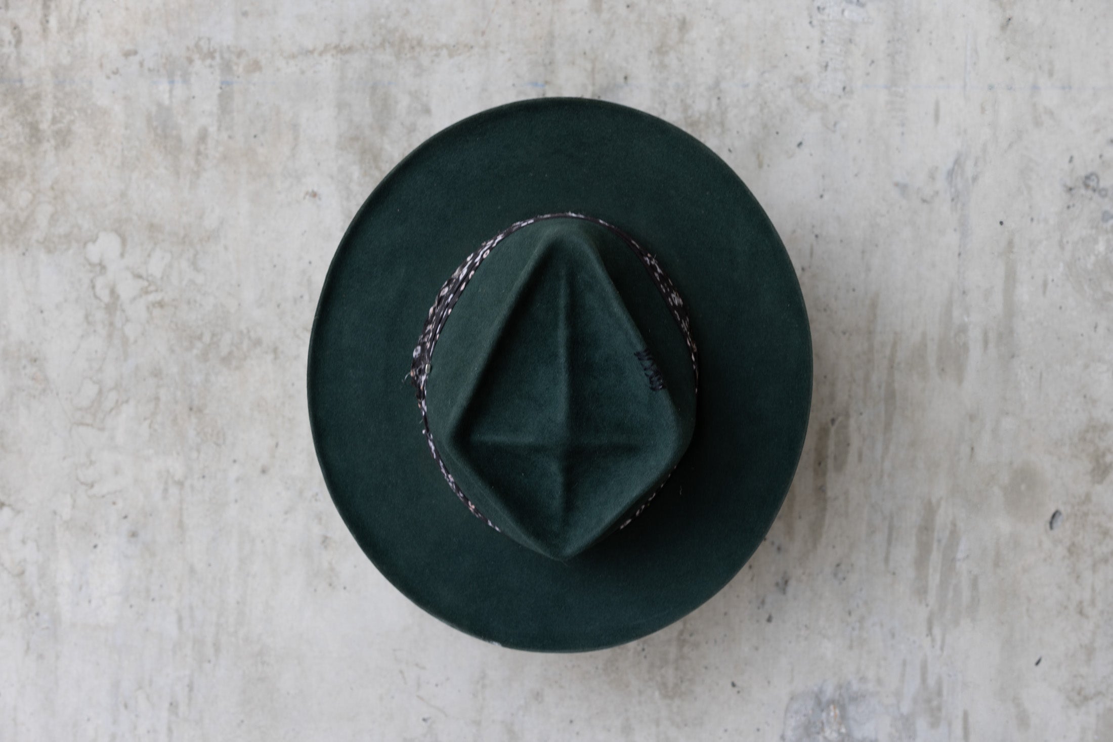 A forest green fedora-style felt hat with a black fabric band top