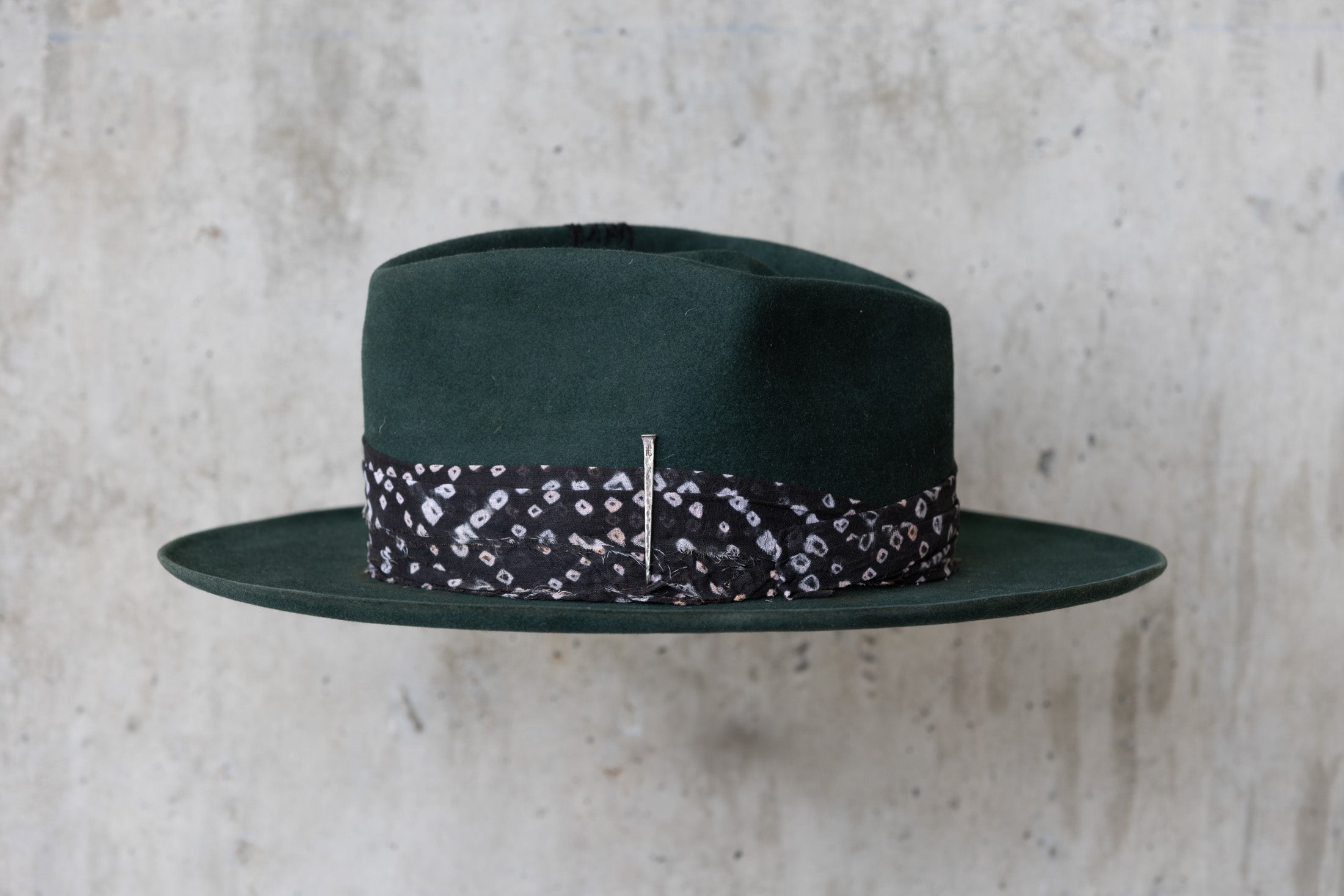 A forest green fedora-style felt hat with a black fabric band left side
