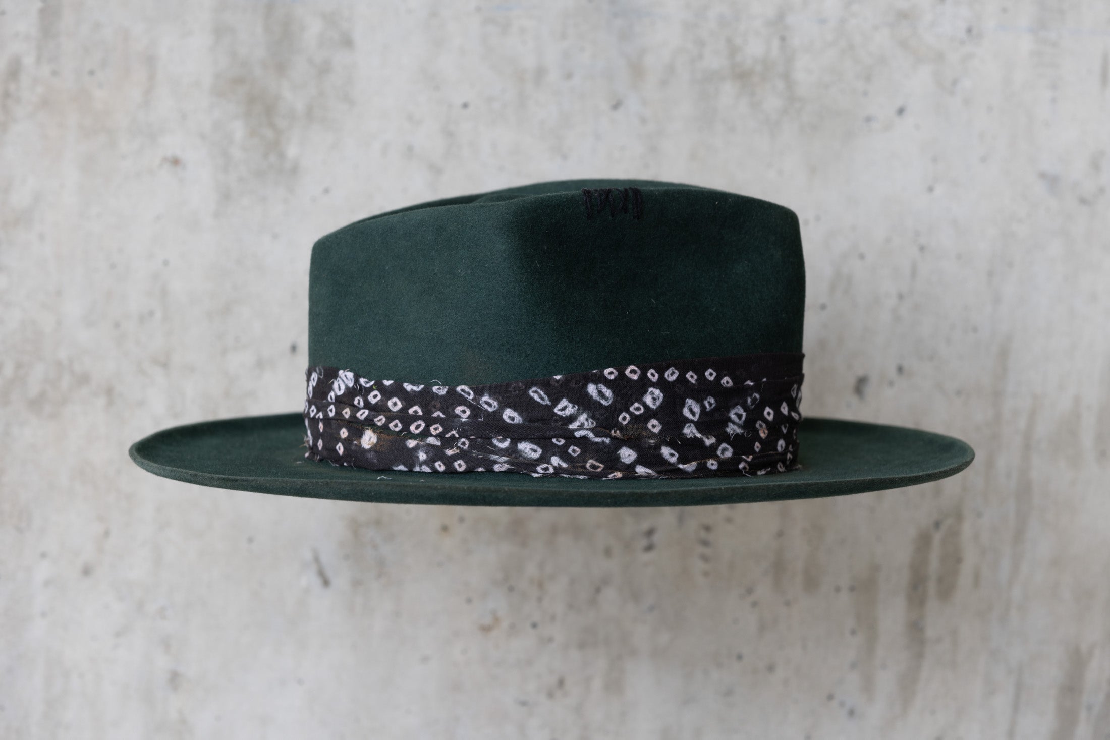 A forest green fedora-style felt hat with a black fabric band right side