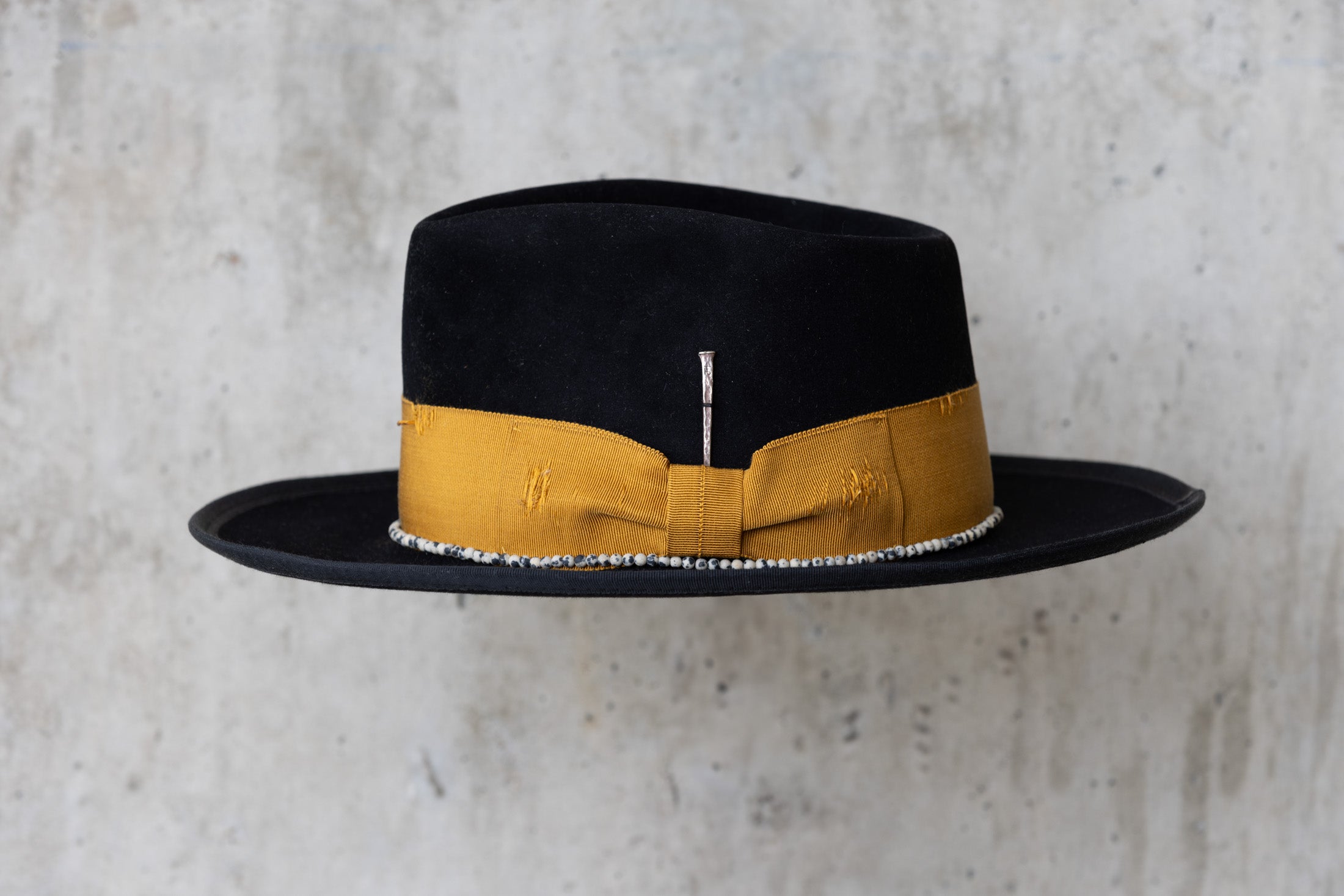 A black beaver felt hat with a yellow band and  a teardrop crown left side