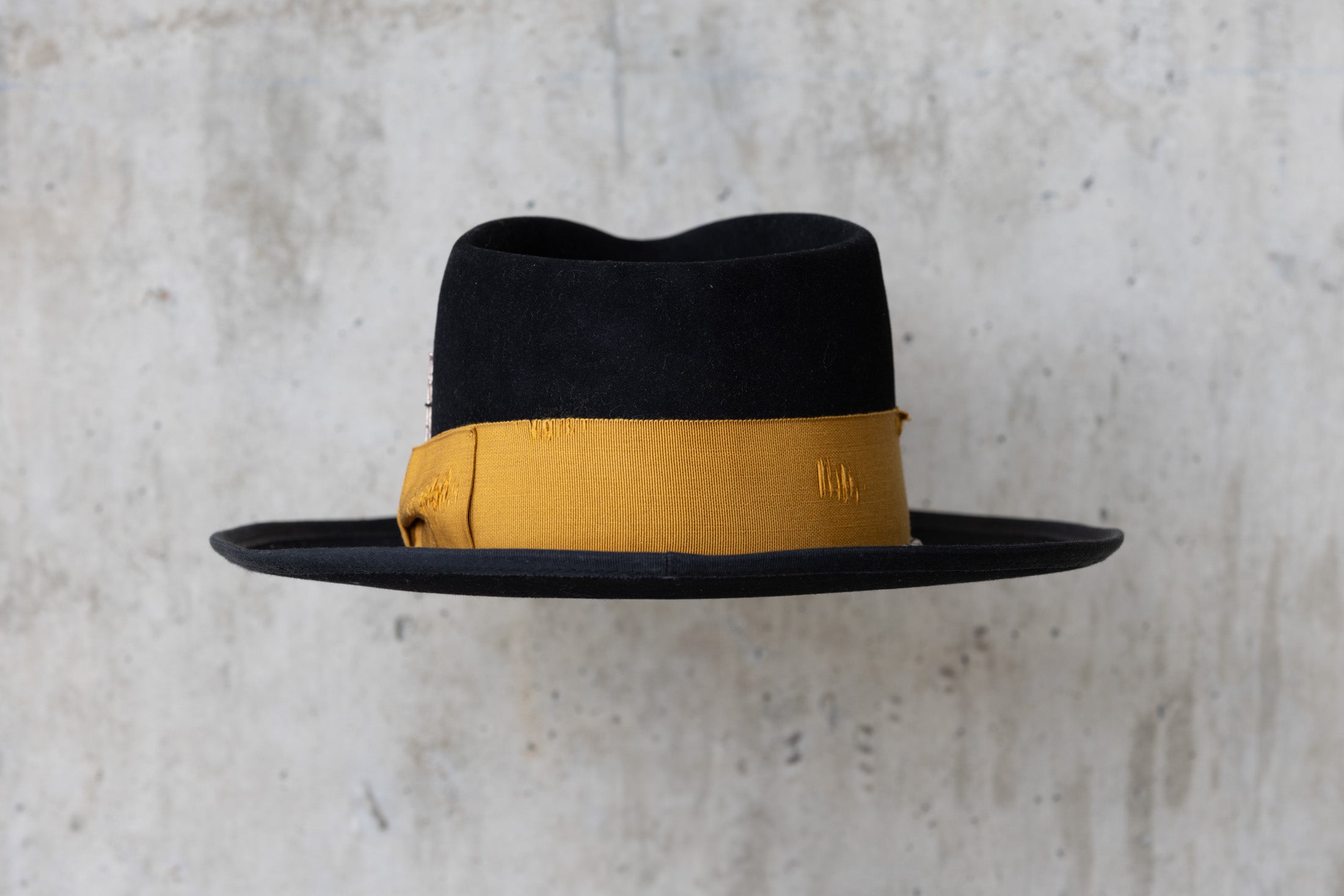 A black beaver felt hat with a yellow band and  a teardrop crown back