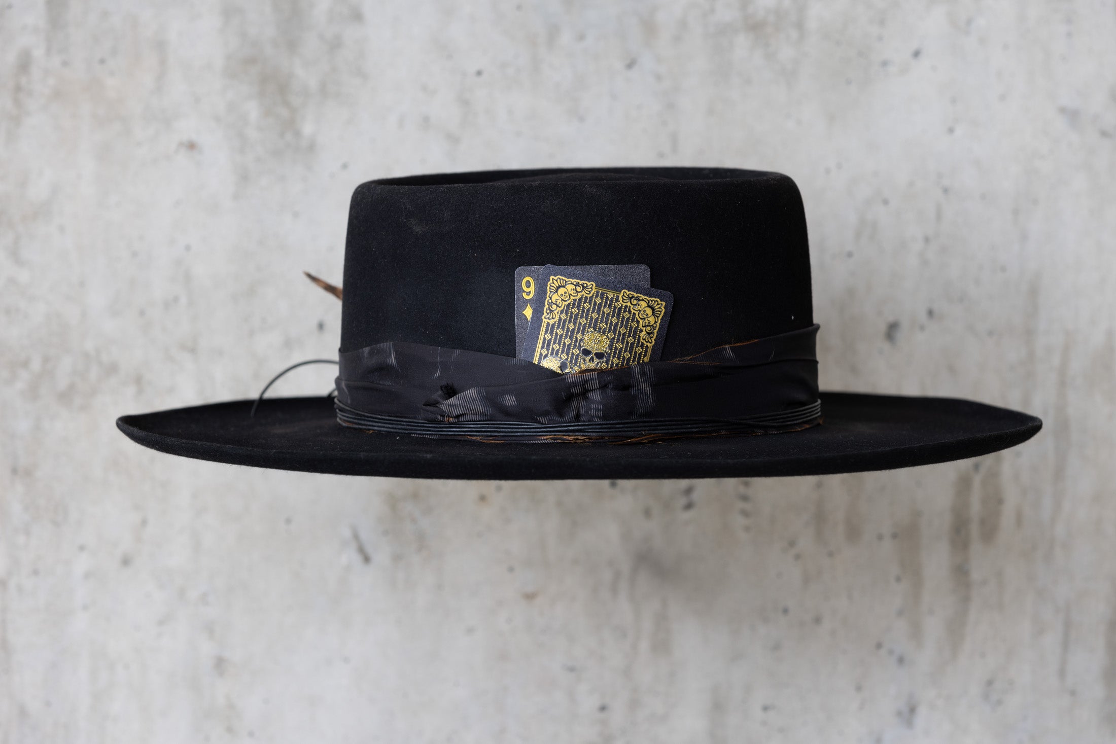 A black Western beaver felt cowboy hat with a wide brim telescope crown and a feather and leather band for men and women right