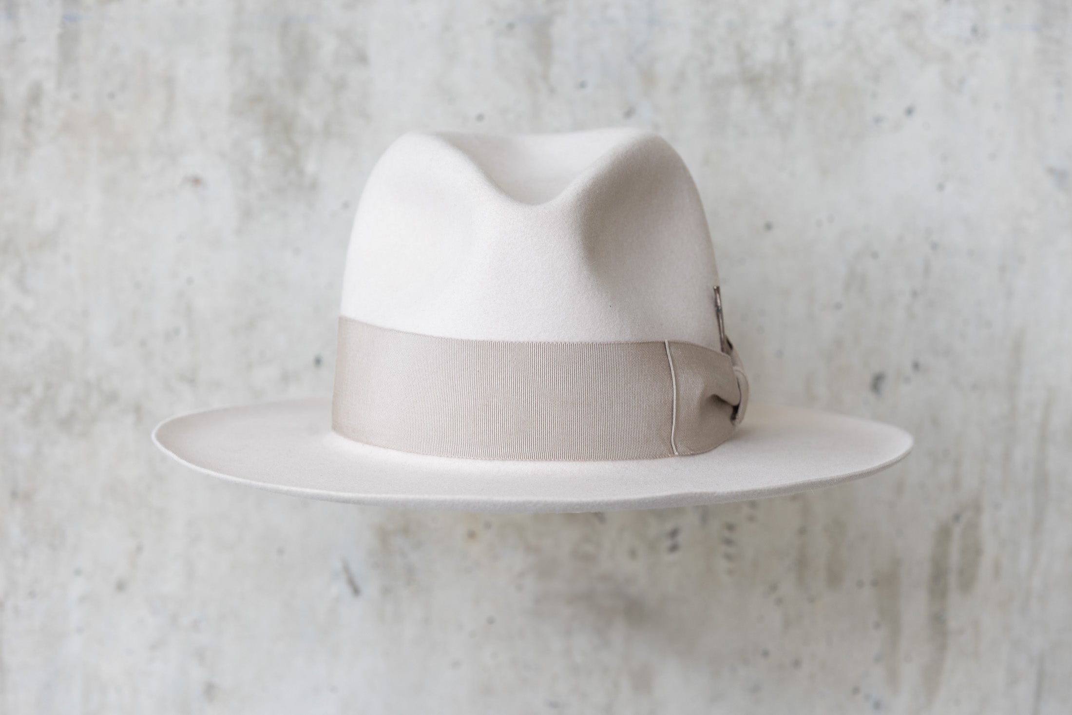 A beige-colored beaver felt hat with a bow and pencil curled brim edge front